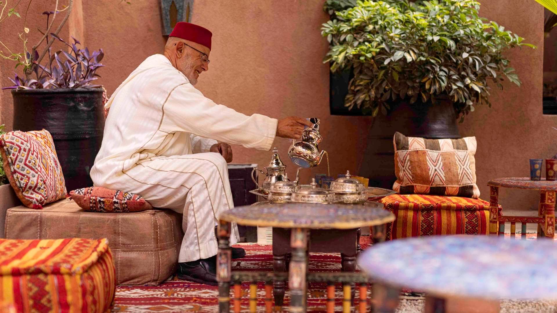 A traditional Moroccan mint tea ceremony, featuring a man pouring tea from a beautifully ornate teapot.