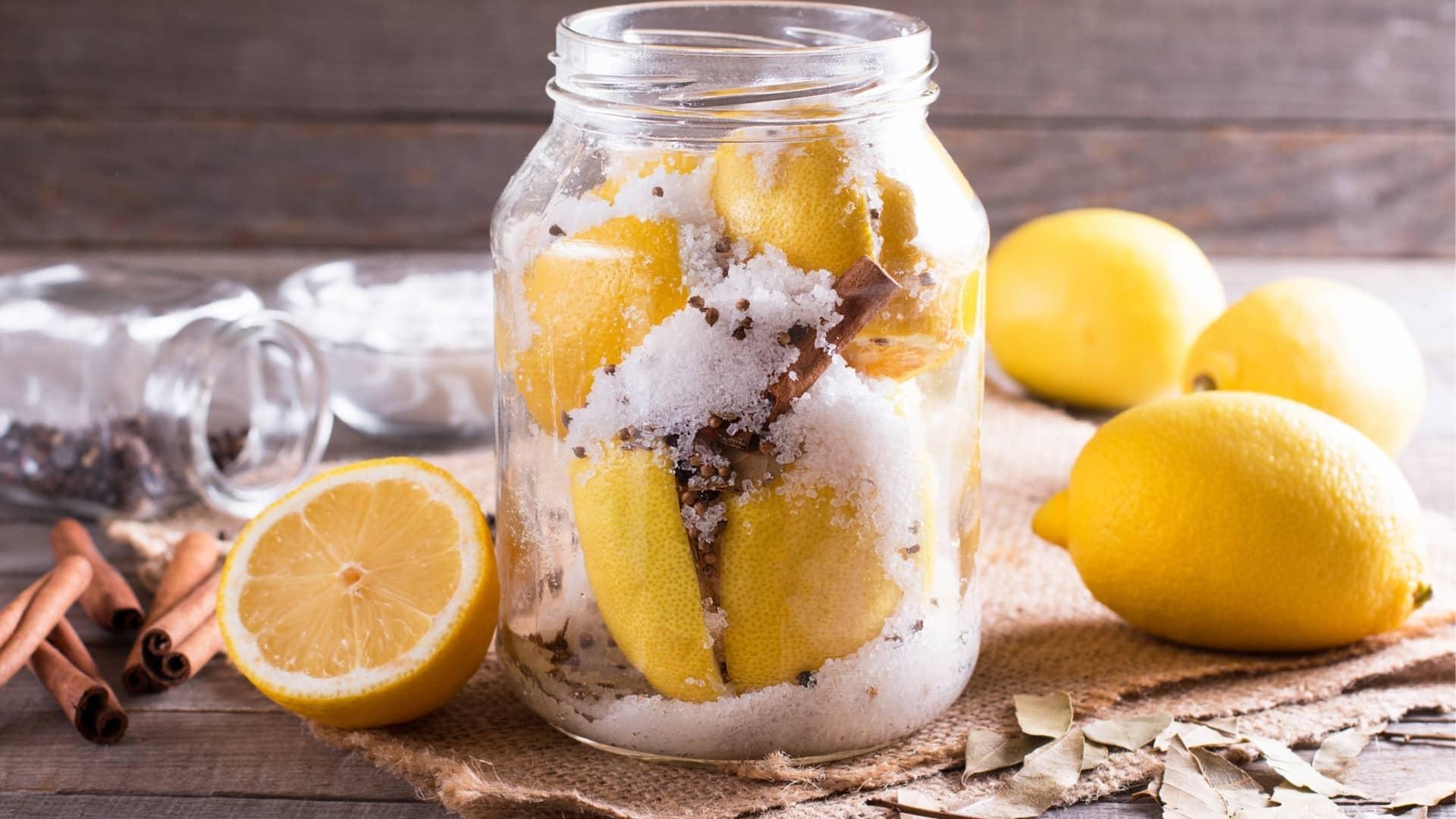 A jar of Moroccan preserved lemons, layered with salt, cinnamon sticks, and spices, ready to add a burst of flavor to traditional dishes.