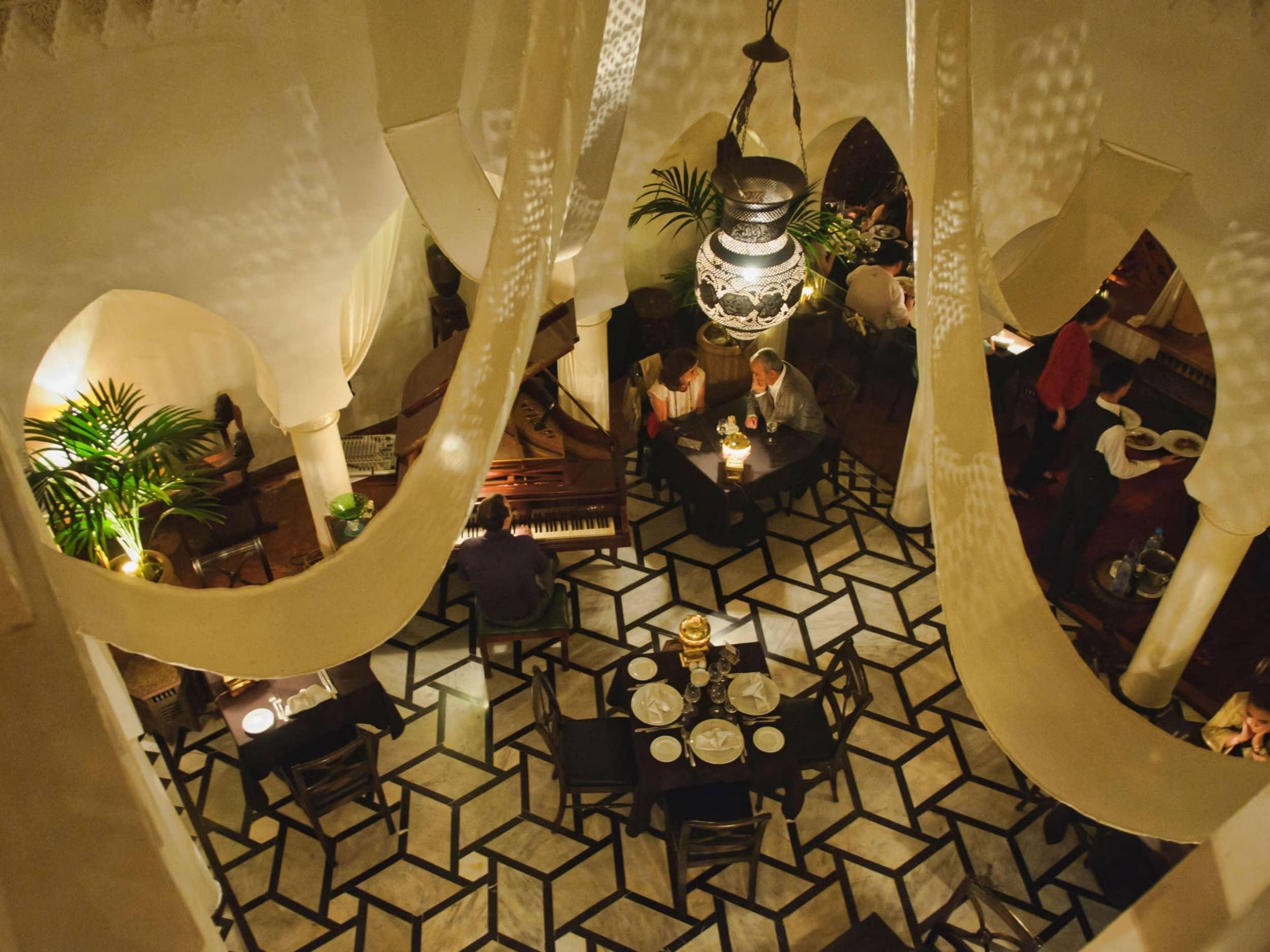 An elegant and atmospheric dining area at Rick's Cafe in Casablanca, featuring live piano music and a classic Moroccan ambiance.