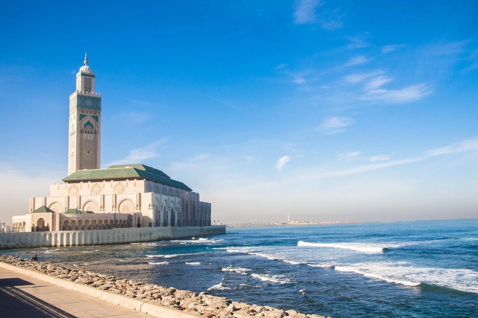 Hassan II Mosque by the sea in Casablanca, with its tall minaret against a clear blue sky.