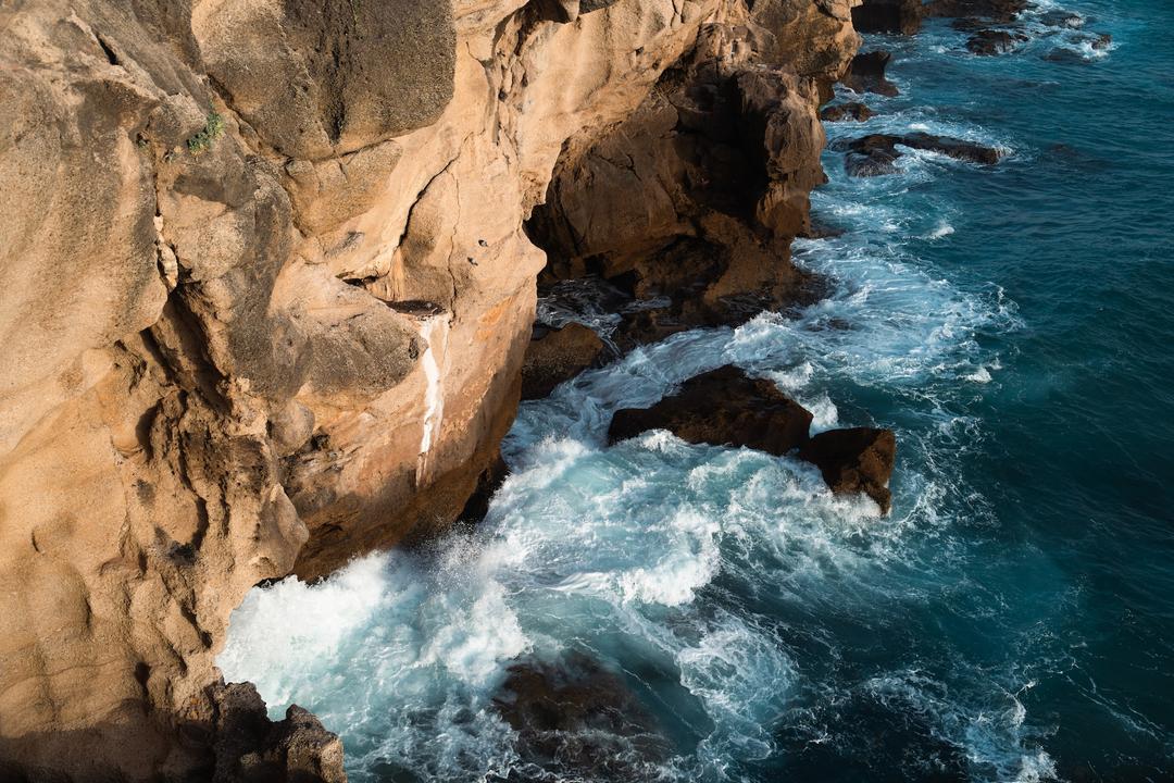 The rugged cliffs of Tangier meet the churning turquoise waters of the sea, highlighting nature's powerful beauty.